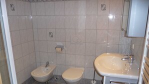 Un baño con bidé, inodoro, lavabo y un perchero para toallas.