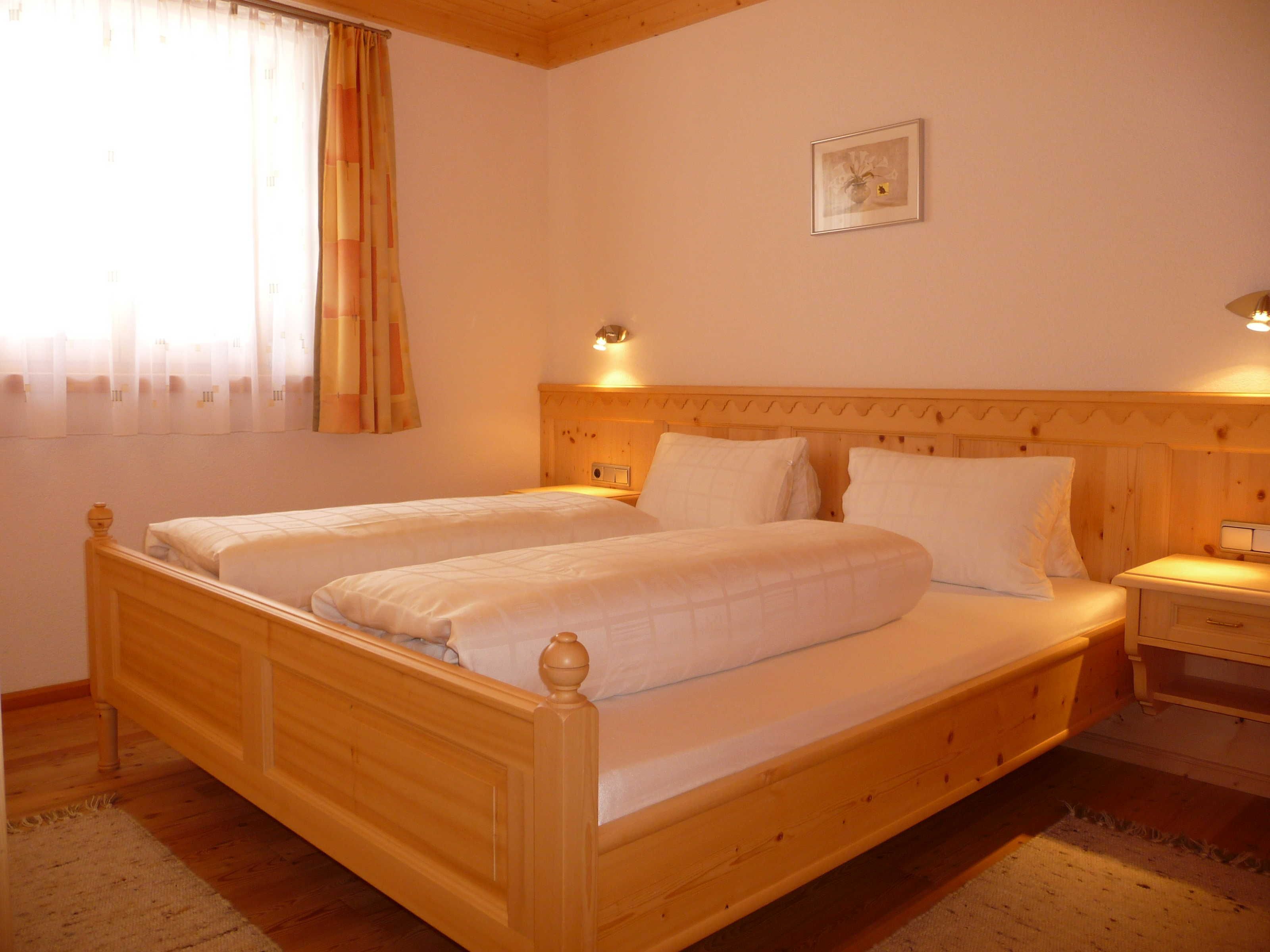 Una cama doble de madera con cabeceros, una mesita de noche y un cuadro en la pared.