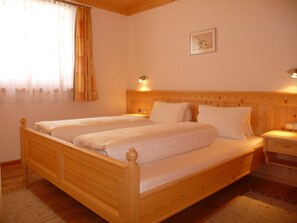 Ein Doppelbett aus Holz mit Kopfteilen, ein Nachttisch, eine Ablagefläche und ein gerahmtes Bild an der Wand.