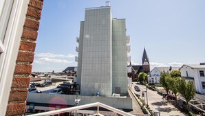 A modern building with a grid-like facade, adjacent to a traditional church with a pointed steeple. - App. Meinecke 29 O, Germany (Sylt)