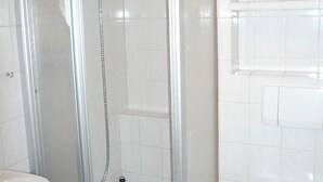 A shower enclosure with a glass door, a showerhead, and a handheld shower attachment. - App. Meinecke 29 O, Germany (Sylt)
