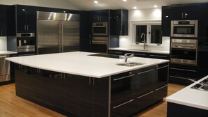 A modern kitchen with dark cabinetry, stainless steel appliances, and a central island with a sink.
