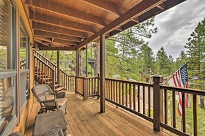 Relax on the deck with a forest view, featuring a staircase and wicker seating area.