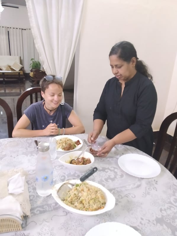 A dining table with plates of food, a water bottle, and a spoon.