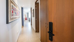 A hallway with a wooden door, a framed artwork on the wall, and a tiled floor. - Top floor 1BR | 2 Pools & Gym | Romantic Zone (Puerto Vallarta)