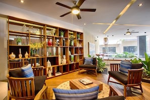 A modern living room with a large wooden bookshelf, comfortable seating, and a view of the outside.
