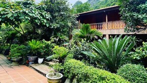 A lush garden with various plants and a wooden building with a balcony. - Lan Homestay (Hai Phong)