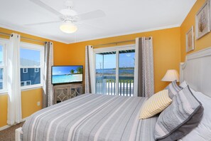 A bedroom with a bed, a TV, a balcony with a view, and a ceiling fan. - Beachfront, Corner Unit, North Cape San Blas - Pelican Crossing (Cape San Blas)