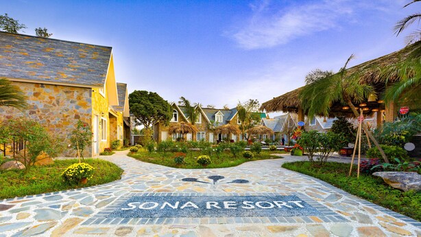 A stone pathway leading to a resort named "SONA RESORT" with tropical landscaping and traditional architecture.