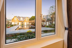 Ein Fenster mit Blick auf ein Haus mit einem Steindach und einem reetgedeckten Aufbau.