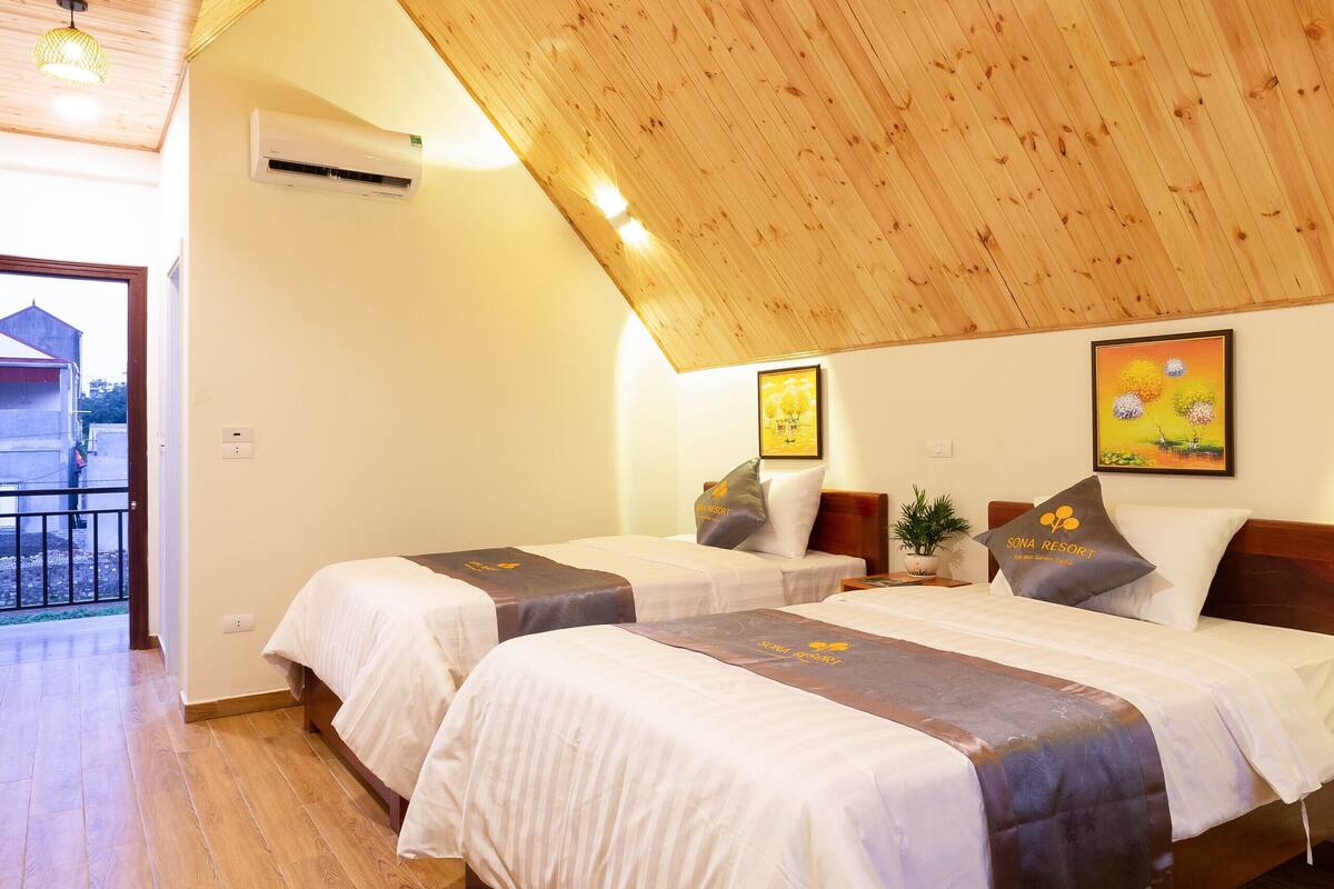 Ein Schlafzimmer mit zwei Betten, Holzboden und Blick nach draußen.