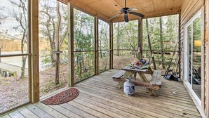 Um deck de madeira com um ventilador de teto, uma mesa de piquenique e um tanque de propano.