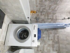 Convenient laundry area with a front-loading washing machine and storage space.