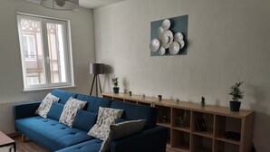 Ein Wohnzimmer mit einem blauen Sofa, einer Stehlampe und einer an der Wand hängenden Dekorationsplatte.
