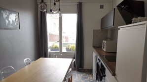Eine kleine Küche mit Holztisch und -stühlen, einem Einbauofen und einem Fenster mit gemusterten Vorhängen.