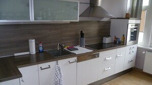A modern kitchen with a stainless steel sink, a built-in oven, and a range hood. - Unique Maisonette Suite for 6 people, Refurbished Historical Villa! Nice Price!! (Bad Salzuflen)
