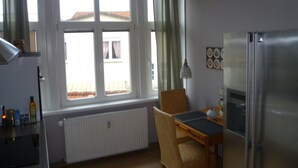 A compact kitchen with a dining table, chairs, a refrigerator, and a window with curtains. - Unique Maisonette Suite for 6 people, Refurbished Historical Villa! Nice Price!! (Bad Salzuflen)