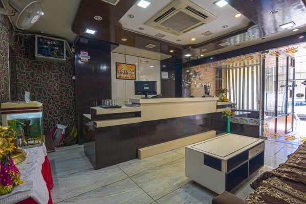 Un área de recepción con mostrador, televisor y planta decorativa.