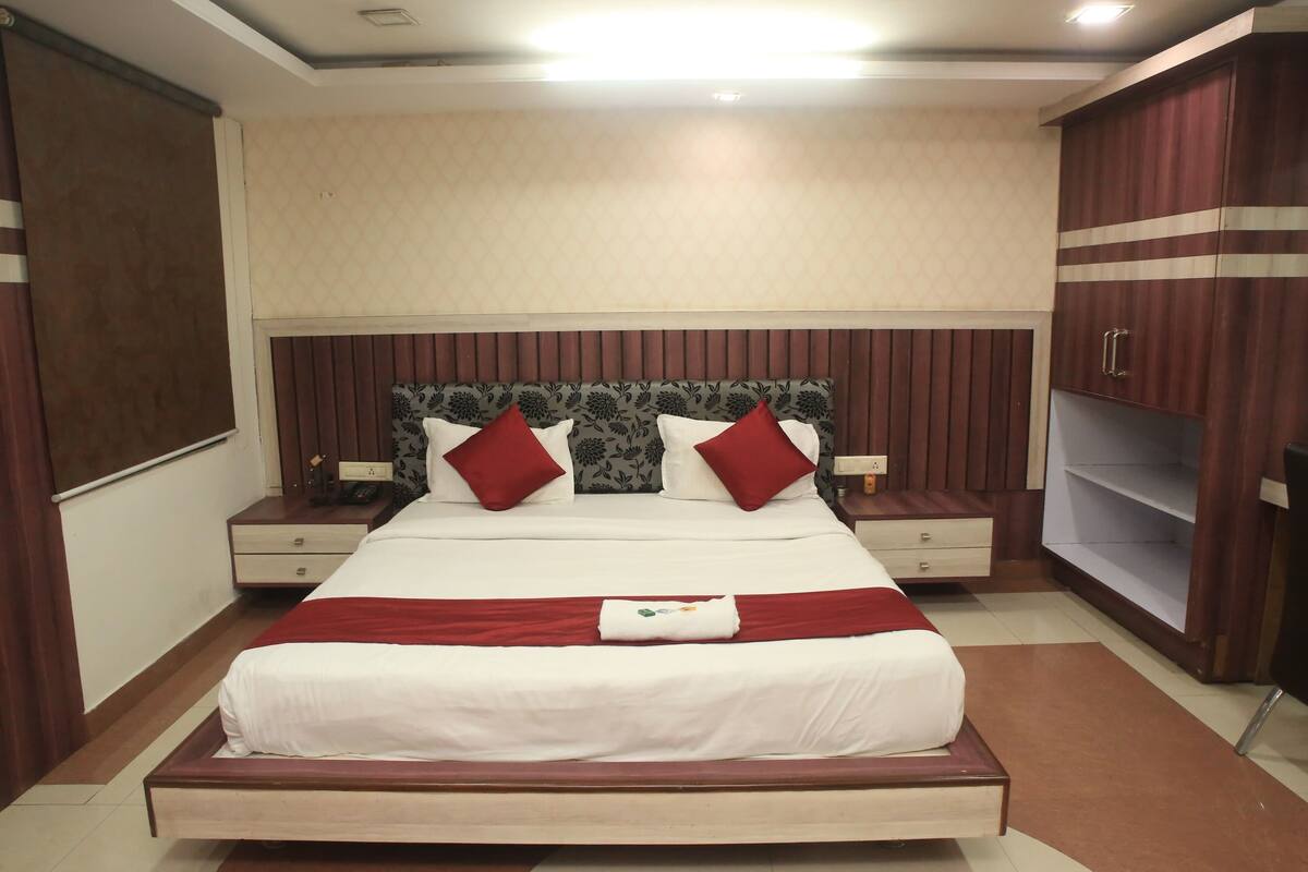 A neatly arranged hotel room with a large bed, two bedside tables, a wardrobe, and a nightstand.