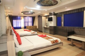 Habitación de hotel con dos camas, un sofá, un televisor y un escritorio.