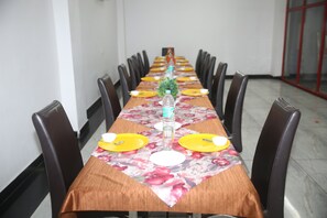 Una larga mesa de comedor con mantel floral, platos amarillos y una botella de agua en el centro.