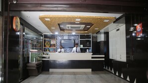 A reception area with a counter, two staff members, a clock, and a decorative ceiling.