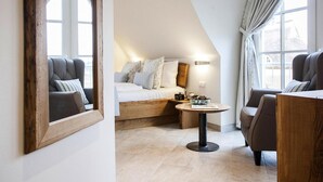 Une chambre confortable avec un plafond en pente, un lit en bois, une petite table ronde et une chaise.