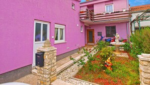 A two-story pink building with a balcony, a small garden with a statue, and a stone wall. - Apartment 782/1828 (Istria - Stinjan), 800m from the beach (Stinjan)
