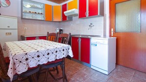 A compact kitchen with red and white cabinets, a wooden ceiling, and a small dining table with a crocheted tablecloth. - Apartment 782/1828 (Istria - Stinjan), 800m from the beach (Stinjan)