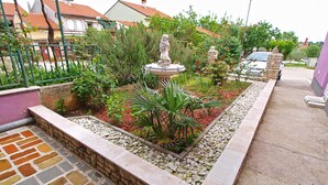 A garden with a statue, a stone wall, and a paved walkway. - Apartment 782/1828 (Istria - Stinjan), 800m from the beach (Stinjan)