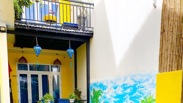 A swimming pool with a tiled deck, surrounded by potted plants and a mural of a beach scene. - Homestay An Bang Sea Adventure (Da Nang)
