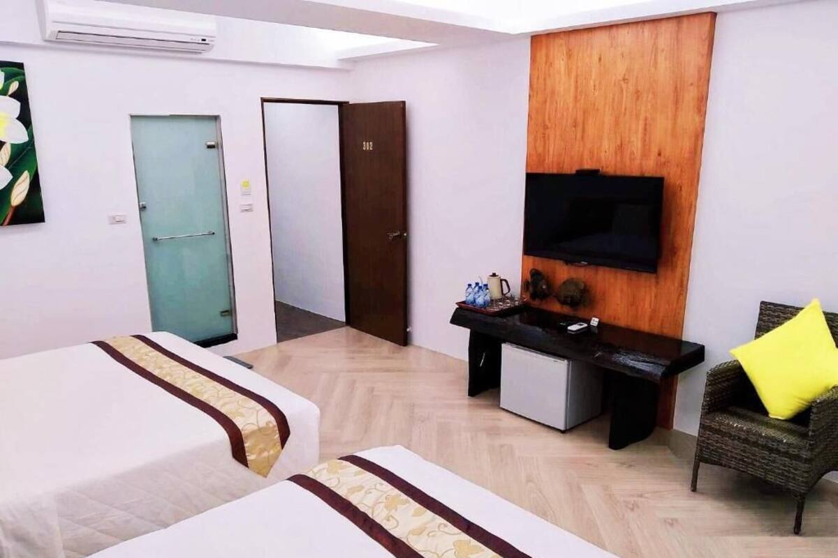 Habitación de hotel con dos camas, un escritorio, un televisor y una silla.