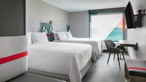 A hotel room with two beds, a desk, and a TV. - avid hotel Roseville - Minneapolis North by IHG (Roseville)