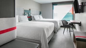 Et hotelværelse med to senge, et skrivebord og et fjernsyn.