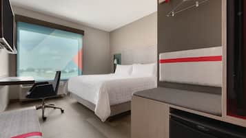 Ein Hotelzimmer mit Bett, Schreibtisch, Stuhl und Blick auf die Stadt.