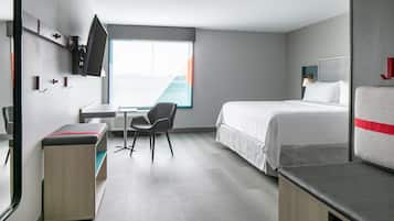Una camera d'albergo moderna con un letto, una scrivania, una sedia e una TV a parete.
