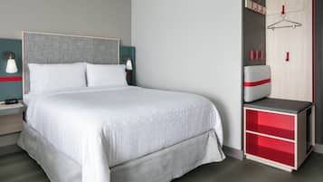 A modern hotel room with a large bed, a wardrobe with red accents, and a bedside table with a lamp.