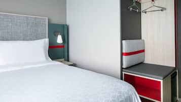 Ett hotellrum med en säng, ett nattduksbord, en stol och en garderob.