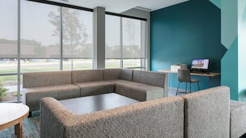 Un espace de bureau moderne comprenant un canapé d’angle, une table basse et un bureau avec un ordinateur.