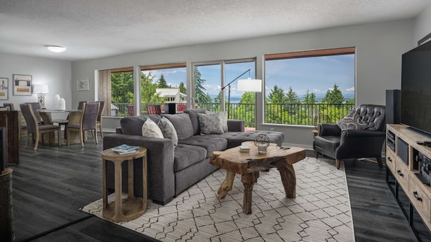 A modern living room with a gray sofa, wooden coffee table, and a TV stand. Large windows offer a view of trees and a house. - Spectacular Views, Single Level w/ Huge Deck & BBQ, Pet Friendly, Next to Forest Park Hiking Trails (Portland)