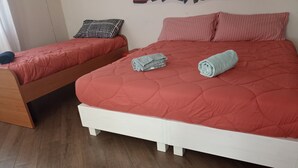 Une chambre à coucher avec un grand lit, un lit plus petit et une table de chevet en bois.