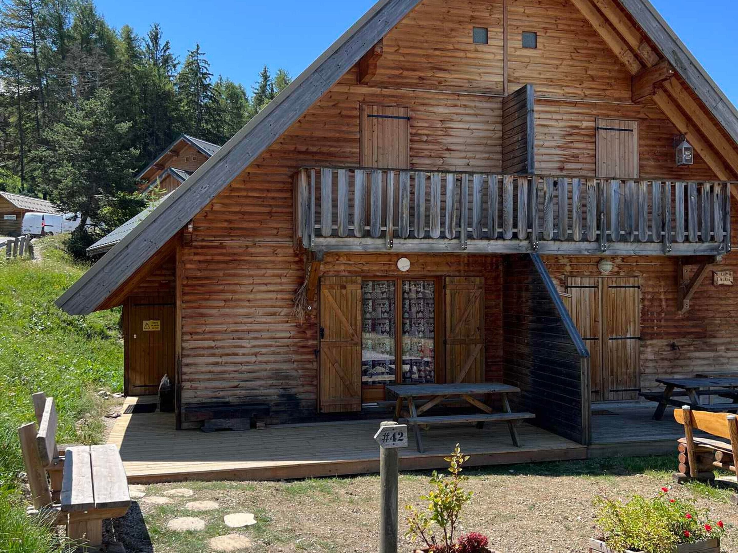 Eine Holzhütte mit Balkon, überdachter Veranda und Picknicktisch.