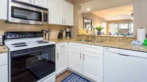 A modern kitchen with white cabinets, a stainless steel oven, a microwave, a coffee maker, and a dishwasher.