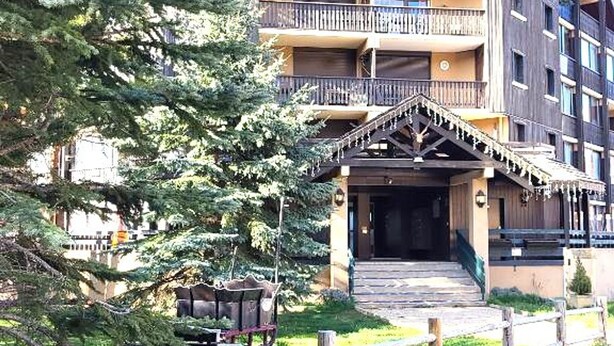 A multi-story building with balconies, a wooden entrance, and a surrounding garden. - Cozy studio 4 pers, piste view, La Joue du Loup (La Joue du Loup)