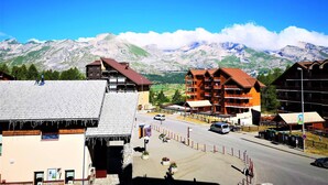 A mountain town with traditional wooden buildings, a central road, and a view of snow-capped mountains. - Renovated 4 ppl apartment with balcony, pets allowed (La Joue du Loup)