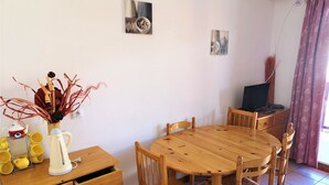 A wooden dining table with six chairs, a wooden cabinet with drawers, a vase with dried plants, and a small table with a kettle and cups. - Renovated 4 ppl apartment with balcony, pets allowed (La Joue du Loup)