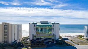A hotel with a modern glass facade, beachfront location, and a view of the ocean.