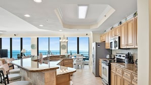 A kitchen with a large island, built-in appliances, and a view of the ocean.