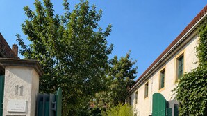 Een keienpad leidt naar een traditioneel gebouw met een groene poort en een bord waarop 'Grosse Halle im Dreudenberg' staat.
