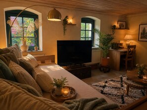 A cozy living room with a sofa, TV, and a dining area with a table and chairs.